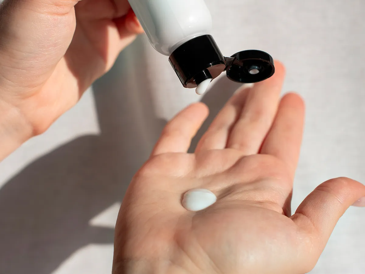 Moisturizer being squeezed onto hand during Korean skincare for men routine