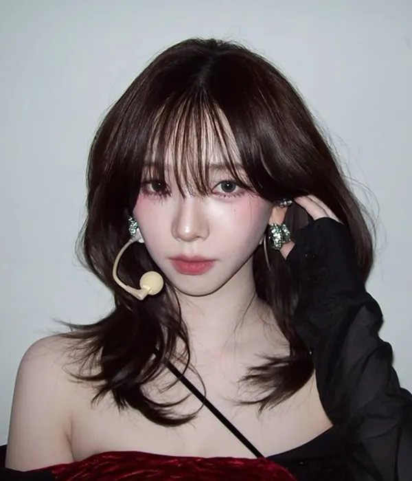 Karina with medium-long hair styled in a hush cut with C-curl waves