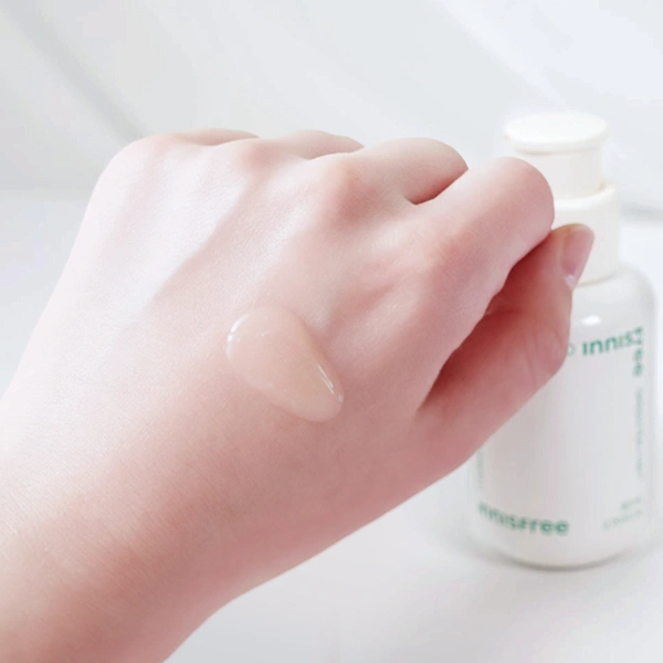Close-up of the colorless, viscous formula of Innisfree Green Tea Serum being applied to the back of a hand.